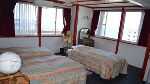 Une chambre avec deux lits, un globe terrestre, un ours en peluche, une commode et de grandes fenêtres avec des rideaux.