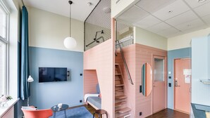 A modern interior with a staircase, a TV mounted on the wall, and a seating area with a chair and a small table. - The Nooq Malmö (Malmö)
