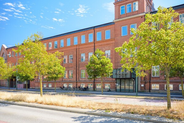 A red brick building with multiple windows and a storefront labeled "Forenom Apartments."