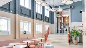 A modern interior with a seating area, tables, and a staircase leading to an upper level. - The Nooq Malmö (Malmö)