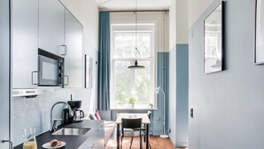 A modern kitchen with a built-in microwave, a coffee maker, and a dining table with chairs. - The Nooq Malmö (Malmö)