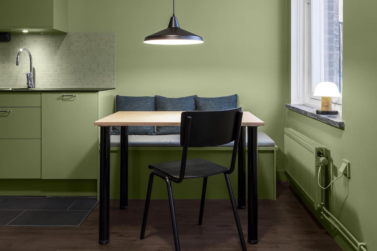 Une cuisine moderne avec une table et des chaises, un luminaire suspendu et une fenêtre offrant une belle vue.