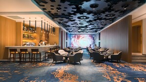 A modern bar area with a unique ceiling design, a seating area with sofas and chairs, and a carpeted floor. - Flyzoo Hotel - Alibaba (Hangzhou)