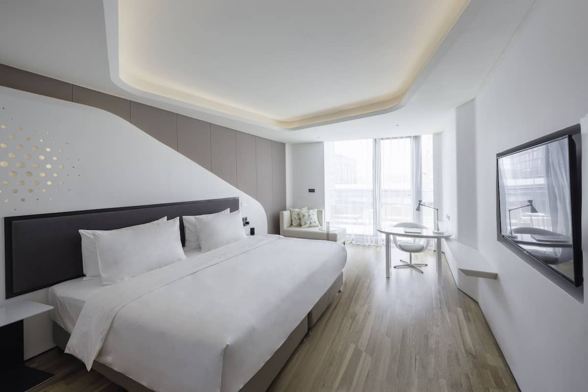 Una habitación de hotel moderna con una cama grande, un escritorio y una silla.