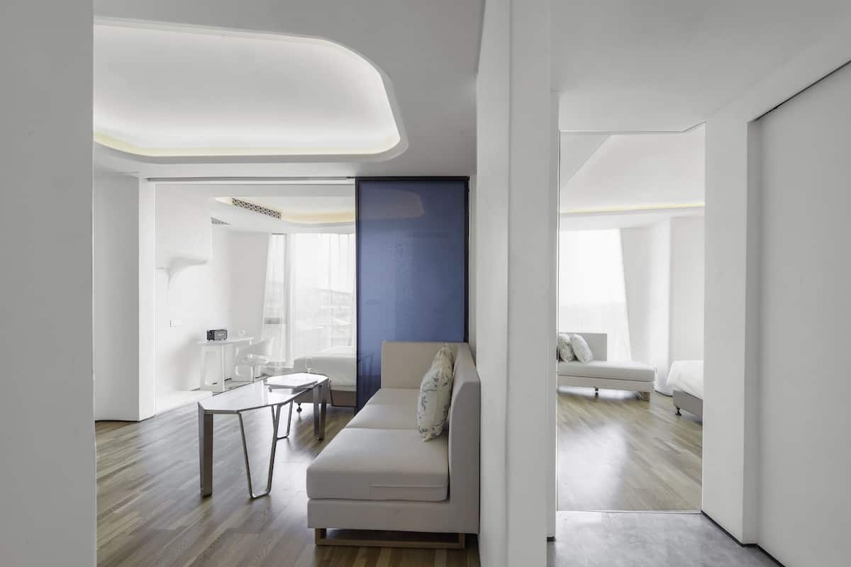 Habitación de hotel moderna con diseño minimalista, que incluye un sofá, una mesita y un separador de vidrio.