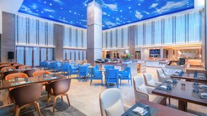 A spacious hotel lobby with a high ceiling featuring a starry sky mural, multiple seating areas with tables and chairs, and a central bar area. - Flyzoo Hotel - Alibaba (Hangzhou)