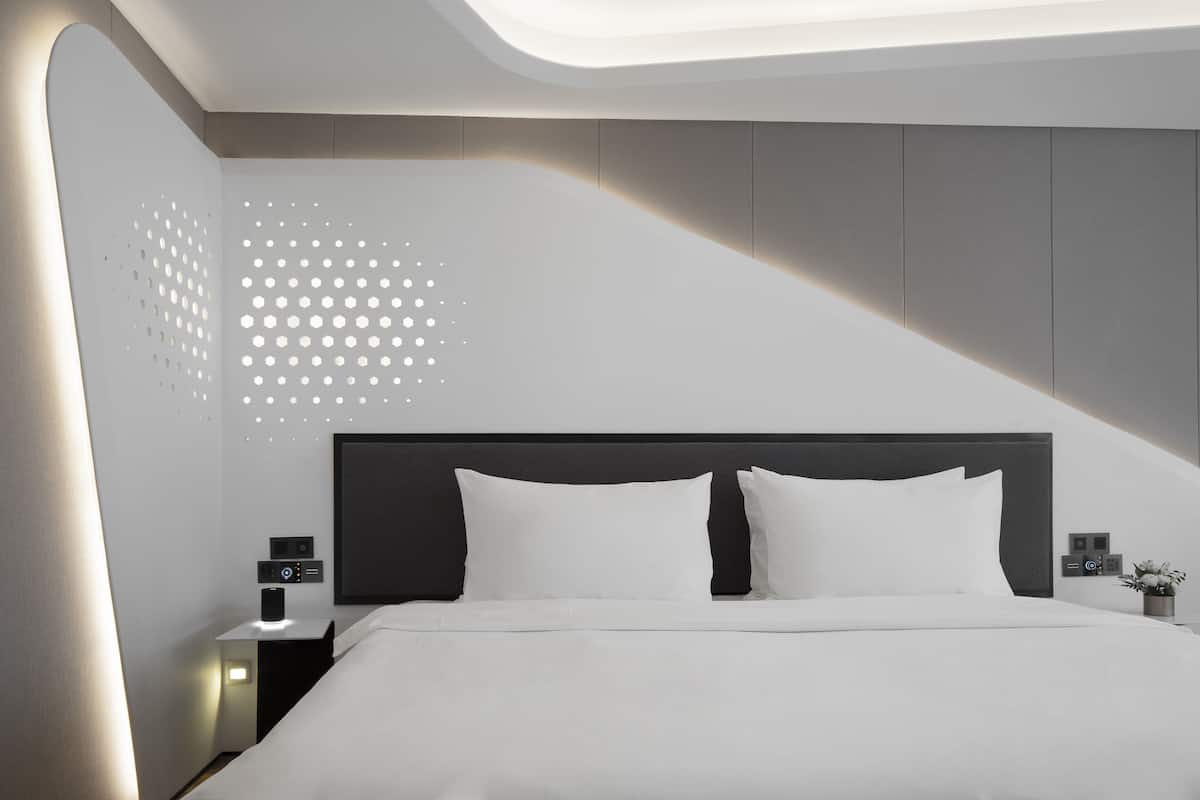 Un dormitorio moderno con una cama, una mesita de noche y una pared con un diseño geométrico.
