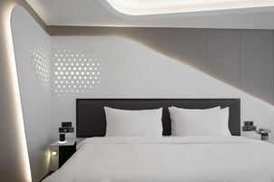 Un dormitorio moderno con una cama, una mesita de noche y una pared con un diseño geométrico.