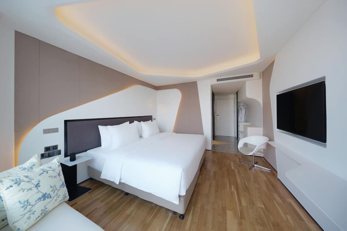 Habitación de hotel moderna con una cama grande, un televisor de pantalla plana y suelo de madera.
