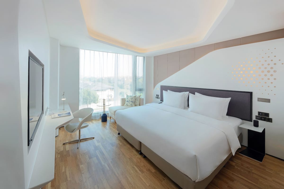Una habitación de hotel moderna con una cama grande, un escritorio y una silla.