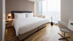 A modern hotel room with a large bed, a desk, and a view of the city. - Flyzoo Hotel - Alibaba (Hangzhou)