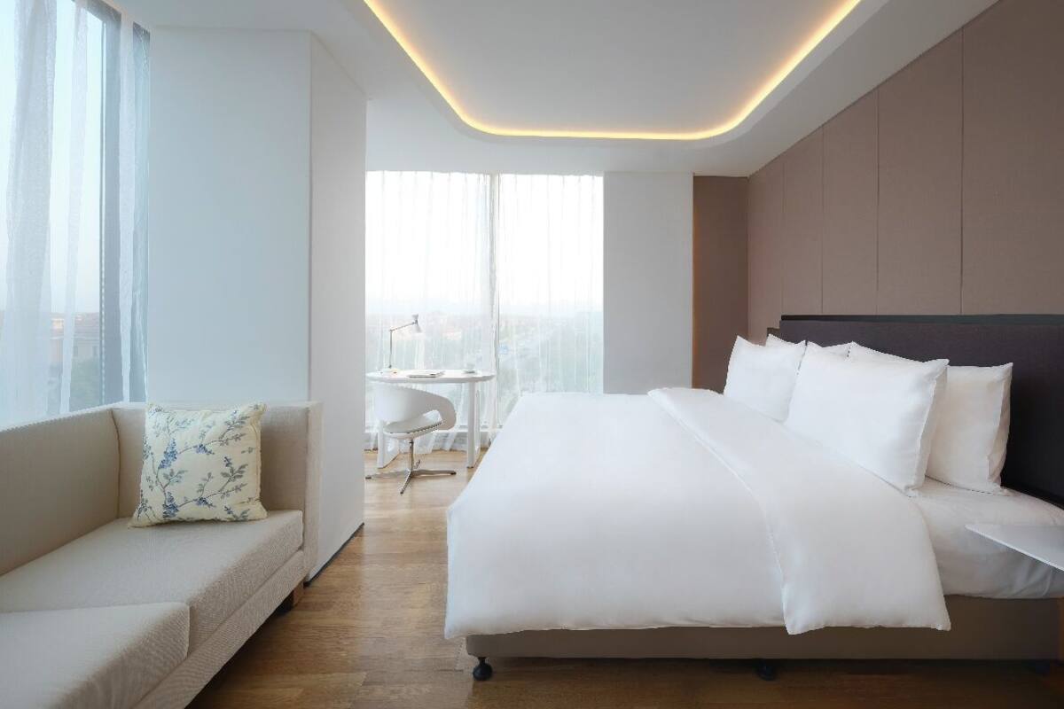 Una habitación de hotel moderna con una cama grande, un sofá y una mesita.