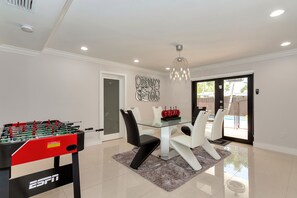 A modern dining area with a glass table, white chairs, and a foosball table. - Tropical paradise wonderful, weekly and monthly discounts available!. (Cutler Bay)