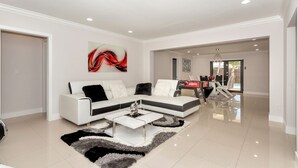 Un salon moderne avec un canapé d’angle blanc, une table basse et un tapis.