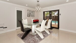 Un espace repas moderne avec une table en verre, des chaises blanches et un luminaire décoratif.