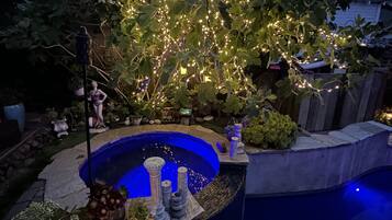 Zwembad met een blauw interieur, omringd door decoratieve planten en stenen constructies.