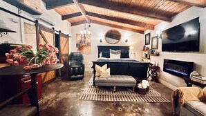 Una habitación amplia con una cama grande, un sillón de masaje, un televisor y una chimenea.
