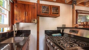 A kitchen with wooden cabinets, a stainless steel sink, and a gas stove.