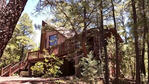 Une cabane dotée d’une terrasse en bois et d’un escalier menant à une fenêtre.