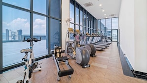 A gym with cardio machines, weight stations, and large windows overlooking a cityscape. - 3 Tower by Plush (Kuala Lumpur)