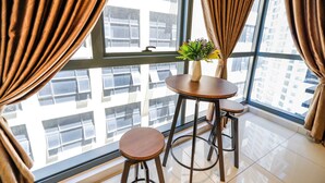 A room with a large window, a round table with two stools, and a potted plant on the windowsill. - 3 Tower by Plush (Kuala Lumpur)