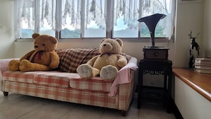 A room with a plaid sofa, two teddy bears, a gramophone, and a deer figurine. - Lohas Gallery Long Stay Hostel (New Taipei City)