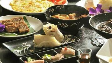Ein traditionelles japanisches Essensarrangement mit verschiedenen Gerichten, darunter Reis, Gemüse und Fleisch, serviert auf schwarz-weißen Tellern.