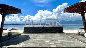 A beachside view with a sign reading "GILLAIR" and a wooden structure. - Gilizen Resort - Private Pool Villas (Gili Air)