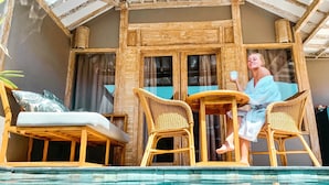 A poolside area with wicker furniture, a glass-enclosed room, and a view of the pool. - Gilizen Resort - Private Pool Villas (Gili Air)