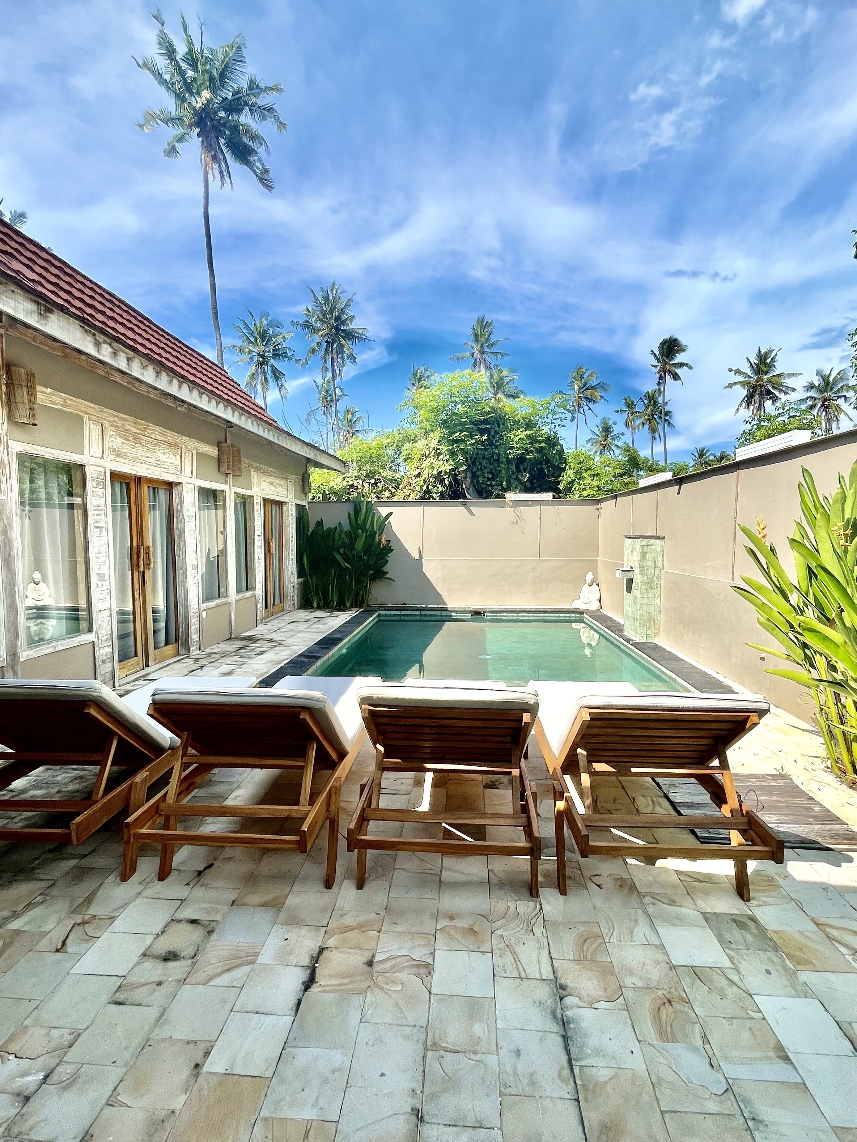 A pool area with lounge chairs, a clear view of the pool, and palm trees in the background.