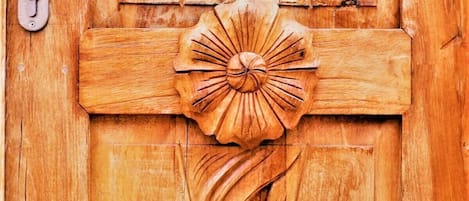 Une porte en bois ornée de sculptures complexes, notamment un motif floral central et des motifs enroulés.