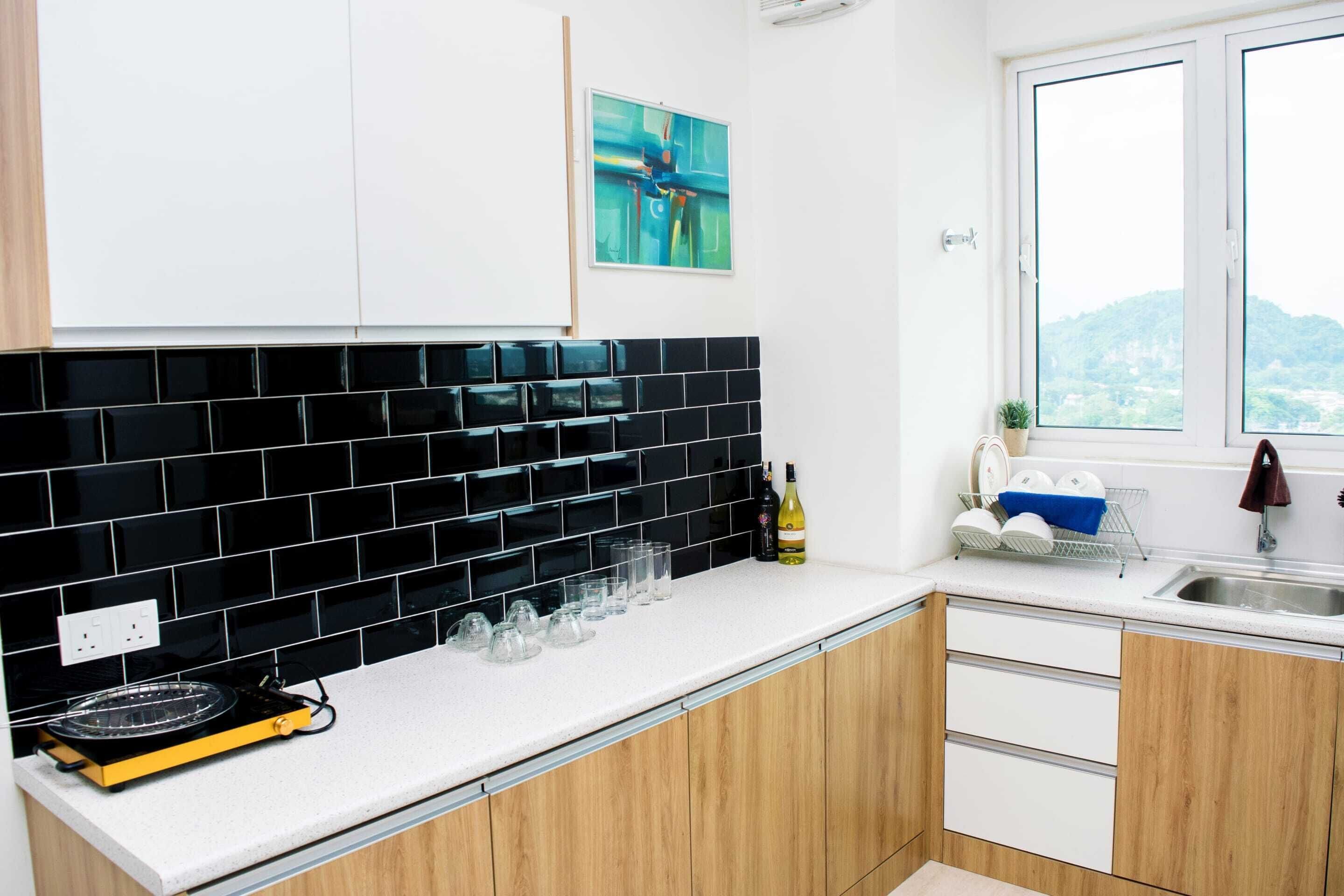 A modern kitchen with black and white tiles, a countertop with glasses, a wine bottle, and a window with a view.
