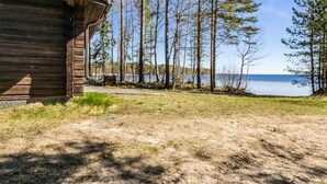 A rustic cabin with a wooden exterior, a gravel path leading to a lake, and tall trees surrounding the area. - Kesäranta 7 by Interhome (Kesälahti)
