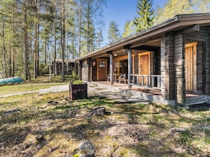 A log cabin with a porch, a fire pit, and a view of the surrounding forest. - Kesäranta 7 by Interhome (Kesälahti)