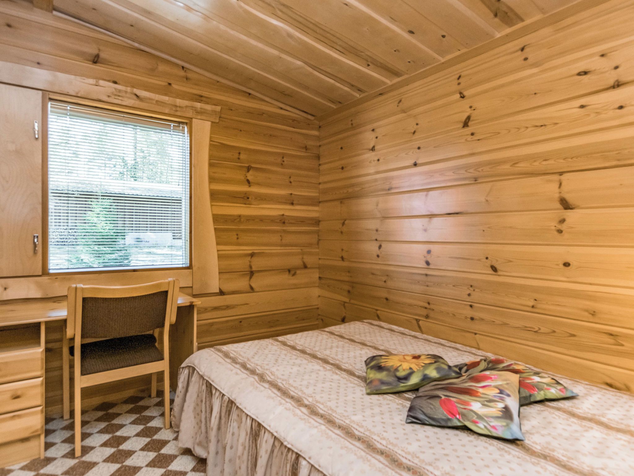 Quarto de cabana de madeira com cama, escrivaninha e cadeira.