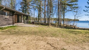 A cabin with a wooden exterior, a porch, and a view of a lake surrounded by trees. - Kesäranta 7 by Interhome (Kesälahti)
