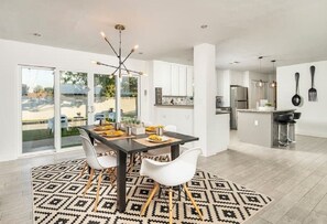 Enjoy meals in this spacious dining area with a large table for four, surrounded by comfortable chairs and a stylish chandelier.