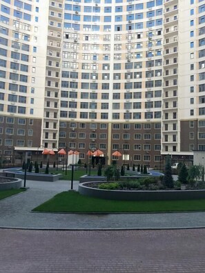 A high-rise building with multiple floors, featuring a central courtyard with pathways and greenery.
