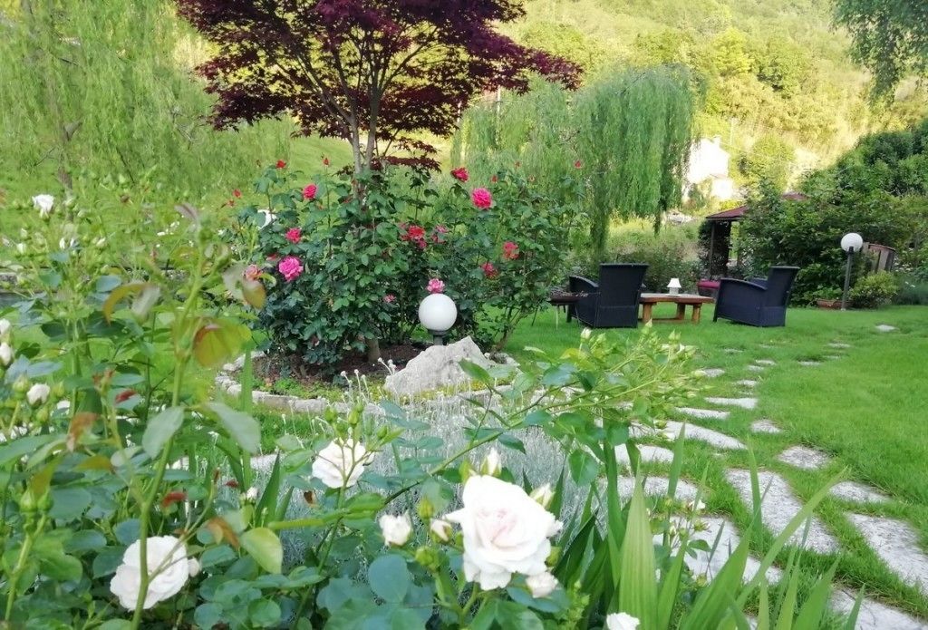 Ein Garten mit verschiedenen Blumen, einem Baum und Gartenmöbeln.