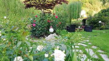 Ein Garten mit verschiedenen Blumen, einem Baum und Gartenmöbeln.