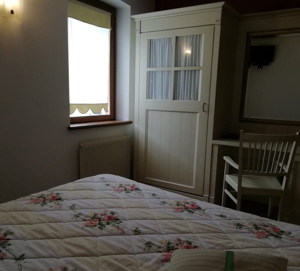 A bedroom with a bed, a wardrobe, a chair, and a window.