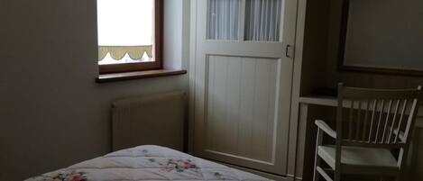 A bedroom with a bed, a wardrobe, a chair, and a window.