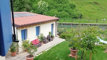 Een huis met een pannendak, een terras met tuinmeubilair en een verzorgd gazon.