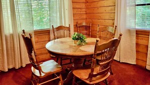 A wooden-paneled room with a round table and six wooden chairs.