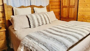 A wooden-paneled bedroom with a bed, pillows, and a nightstand.