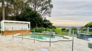 Un área de piscina moderna al aire libre con sillones de descanso y una terraza de madera.