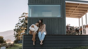 Un edificio moderno con un amplio ventanal y un espacio exterior cubierto con sillas.