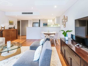 A modern living room with a sofa, TV, and a glass coffee table.