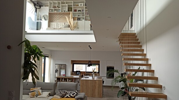 A spacious living area with a high ceiling, a modern staircase, and a kitchen in the background. - Villa of archi 180m2 new (Saint-Aunès)