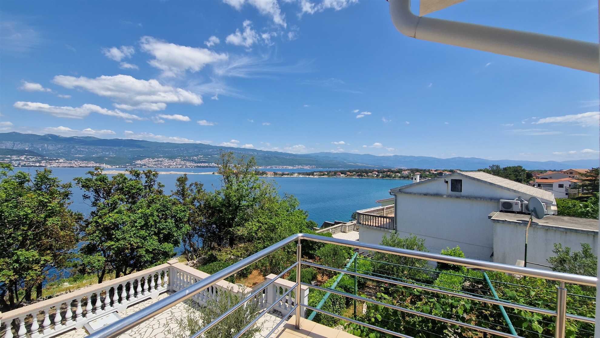 Une vue sur la côte, avec un ciel dégagé, un balcon doté d’une balustrade et une vue lointaine sur la ville.